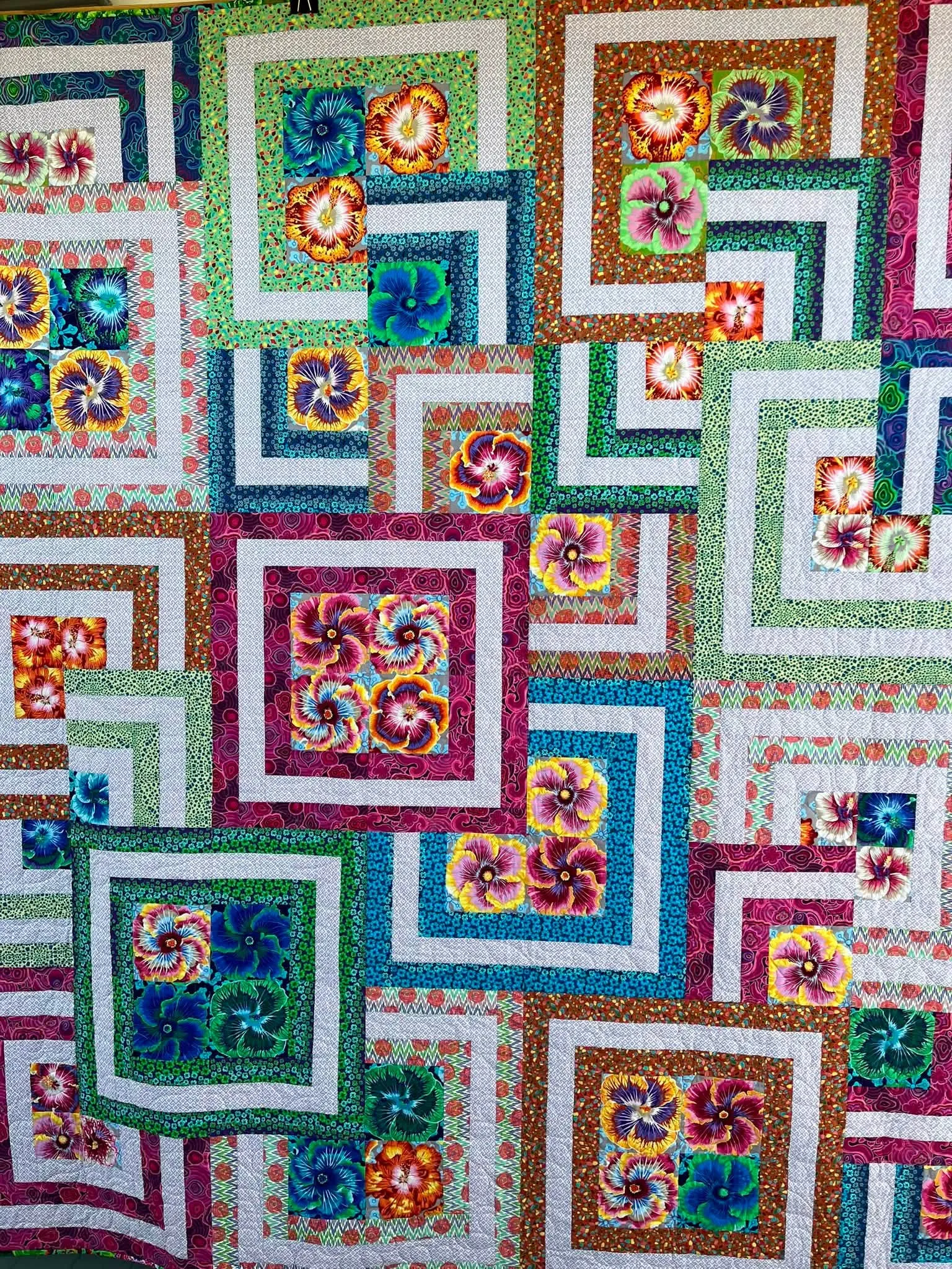 Colorful geometric quilt of nested squares in bright multicolor prints