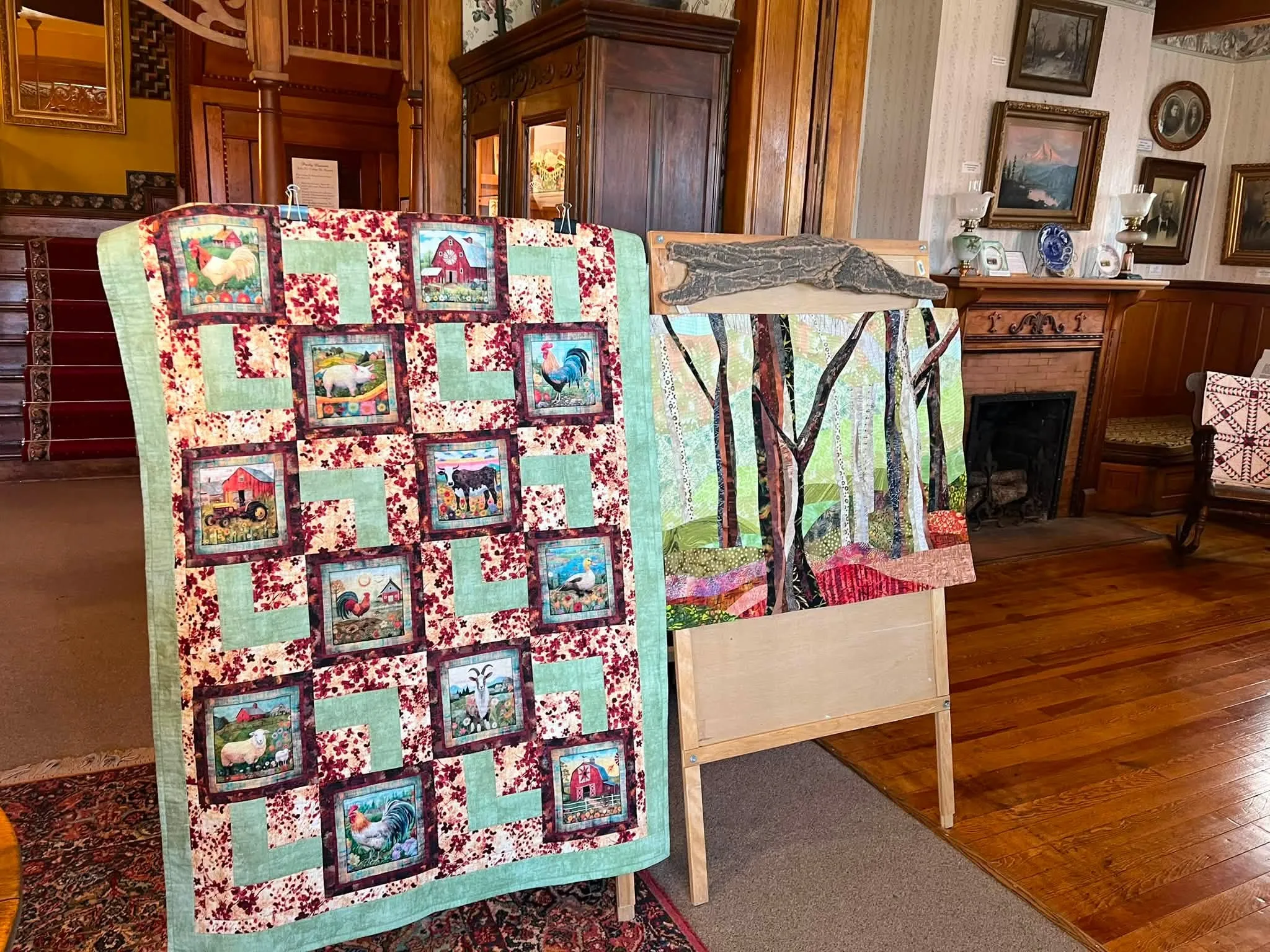 Quilts with scenic blocks and appliquéd trees displayed in the museum's Victorian parlor