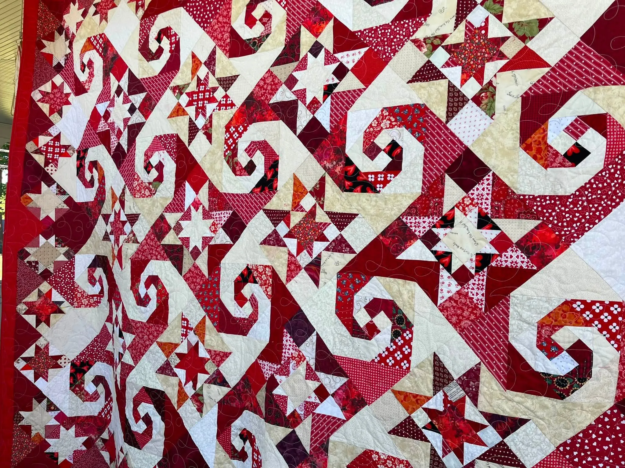Red and white quilt with pinwheel swirls and sawtooth stars