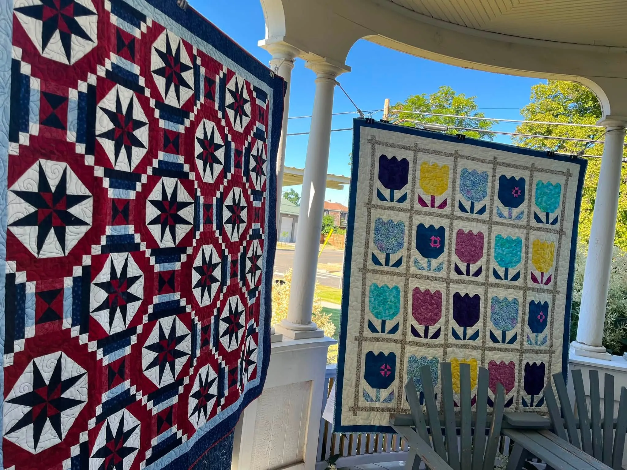 Tulip appliqué quilt and a navy star medallion quilt on the museum porch